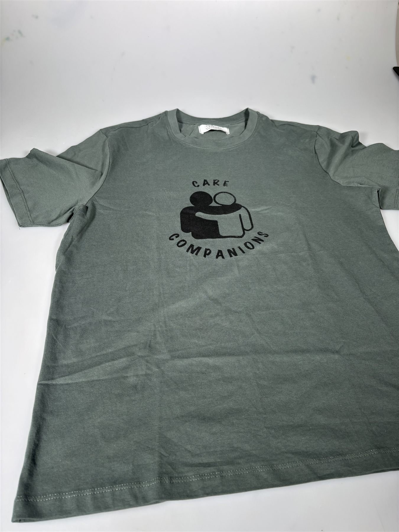 Care Companions logo screen-printed on a sage green T-shirt